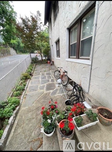 A white house with a stone pathway and red flowers.