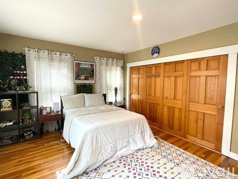 A bedroom with a large bed and a Christmas tree in the corner.