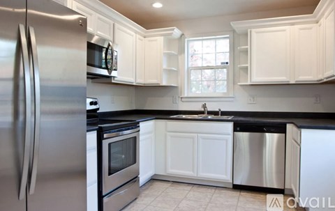 A kitchen with white cabinets and a stainless steel refrigerator.