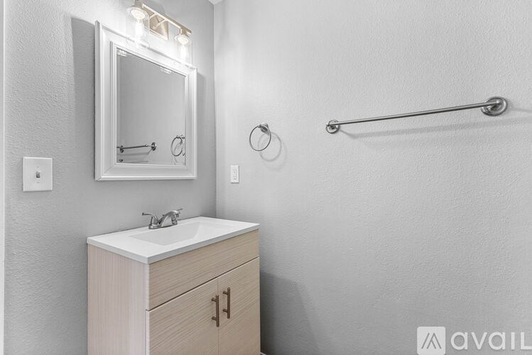 A bathroom with a sink, mirror, and a towel bar.