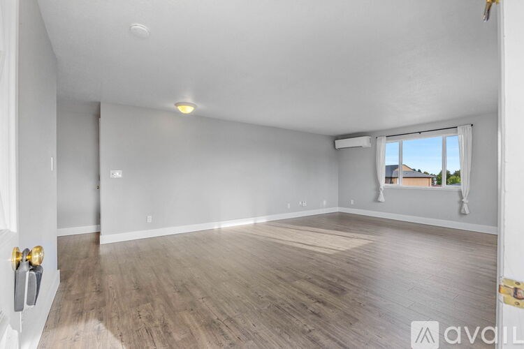 A spacious room with wooden flooring and white walls.