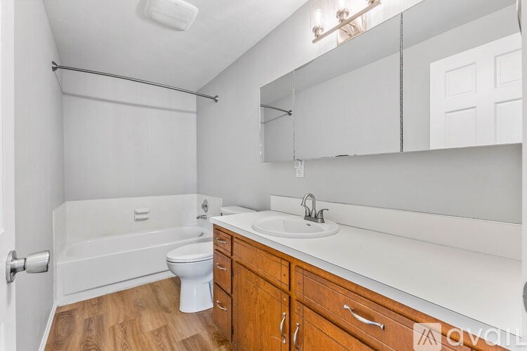 A white bathroom with wooden cabinets and a white toilet.