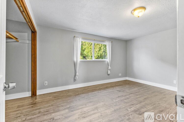 A room with a window and a wooden floor.