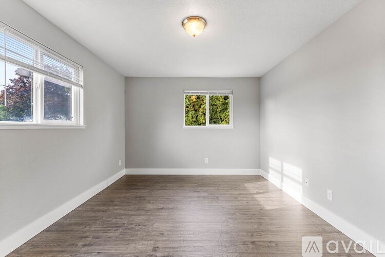 A room with wooden flooring and a window showing greenery outside.