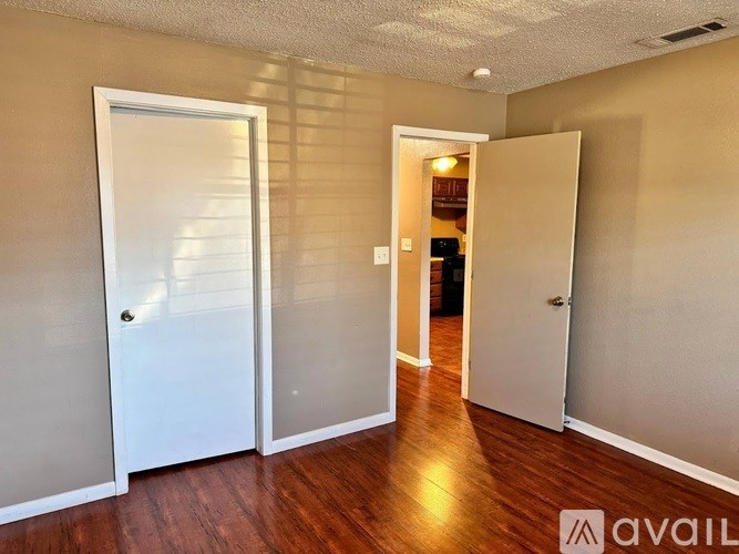 A room with two white doors and a wooden floor.
