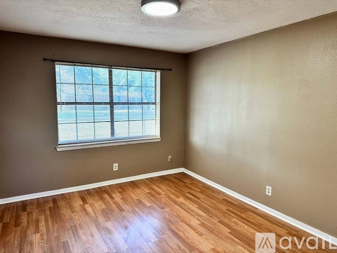 A room with a window and wooden flooring is available for rent.