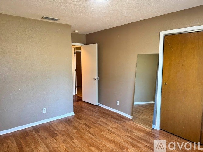 A room with wooden floors and two doors, one of which is open.