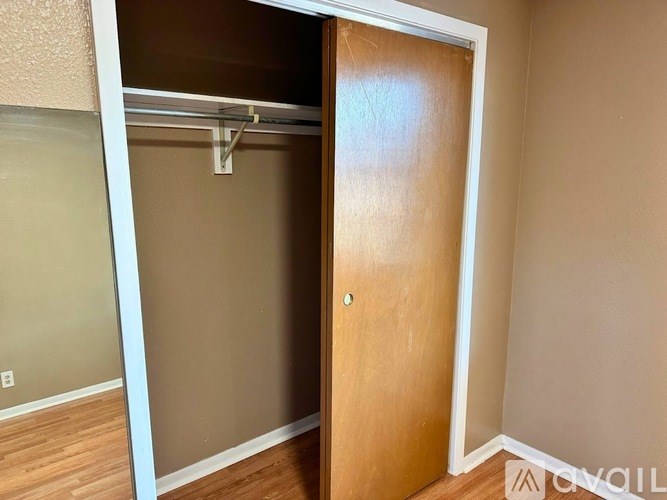 A brown door is open to a room with a white wall.