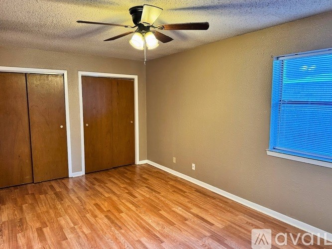 A room with a ceiling fan and wooden floors.