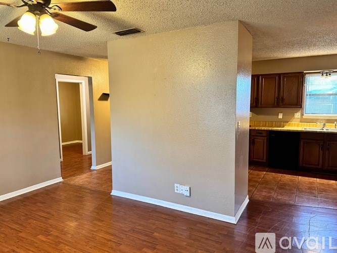A room with a ceiling fan and a wall with a switch.
