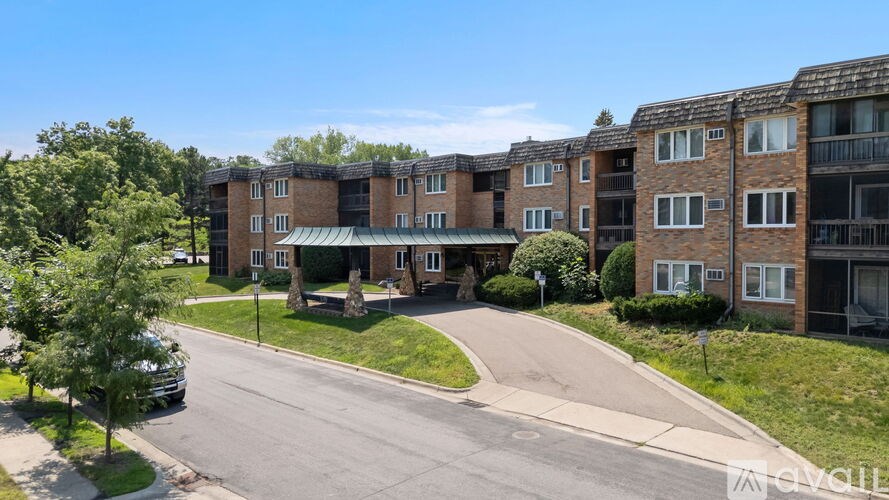 Apartment complex with a green roof and a tree in front.