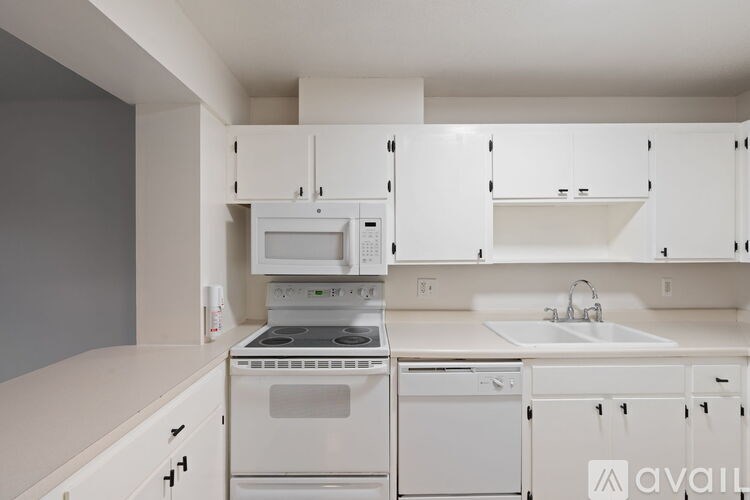A white kitchen with a microwave, oven, and dishwasher.