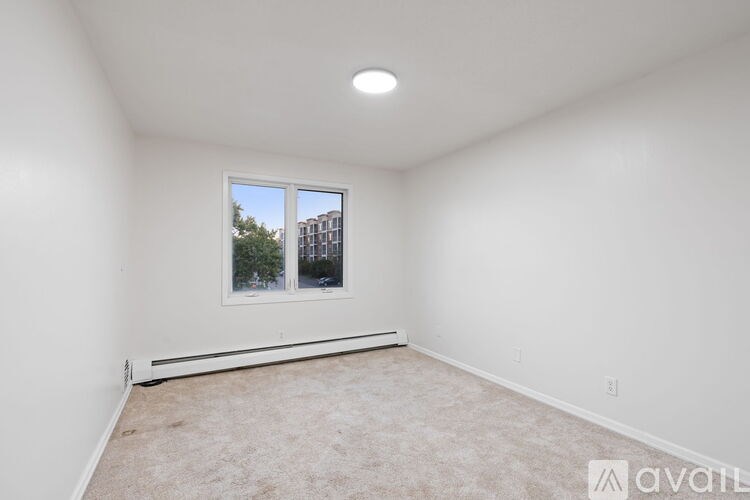 A room with a window and a carpeted floor.