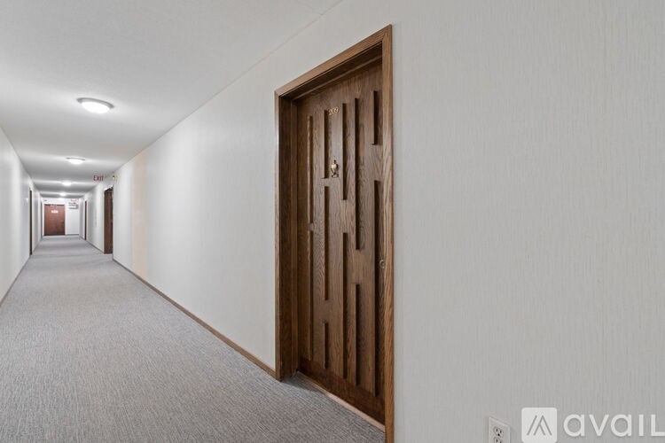 A long hallway with a brown door on the right.