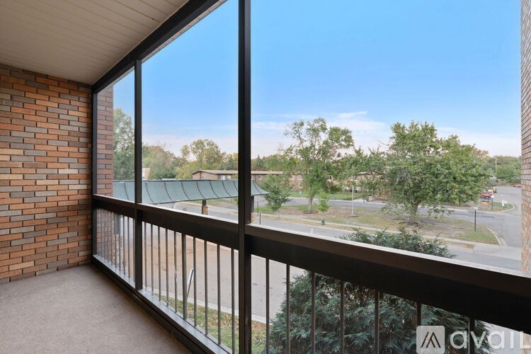 A balcony with a view of a street and trees.