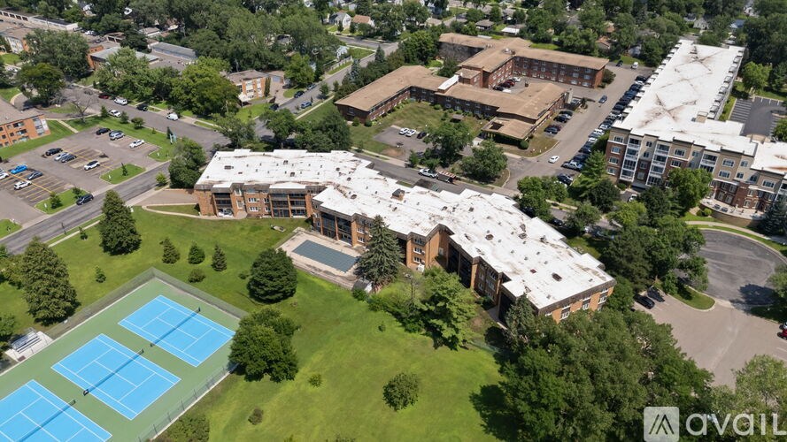 An aerial view of a building with a tennis court in front.