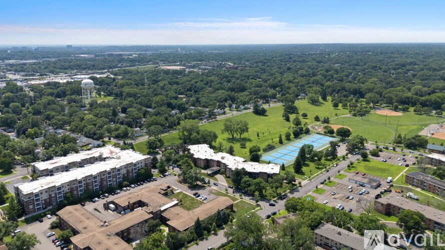 An aerial view of a campus with buildings, a pool, and a parking lot.