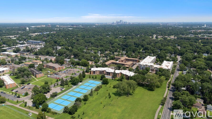 An aerial view of a large green field with a swimming pool and buildings in the distance.
