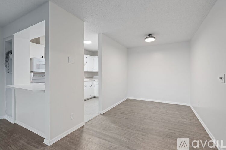 A spacious, empty room with wooden flooring and white walls.