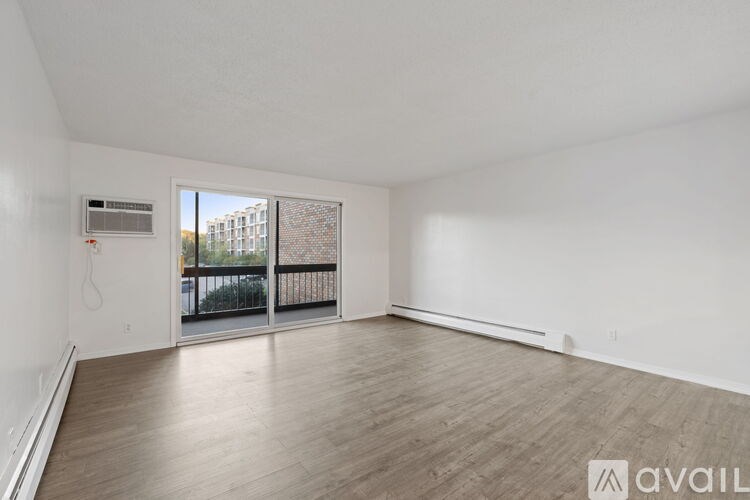 A spacious room with wooden flooring and a balcony with a railing.