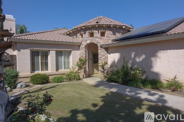 A house with a garden in front and a clear blue sky above.