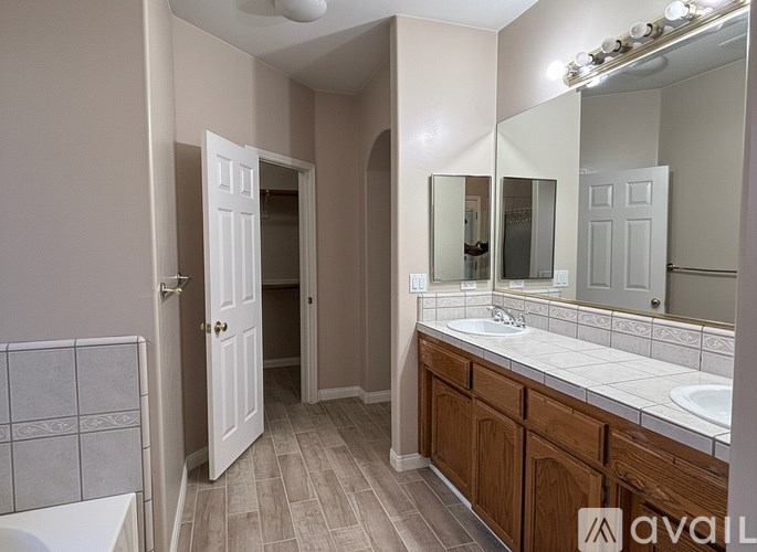 A bathroom with a white sink, mirror, and wooden cabinets.
