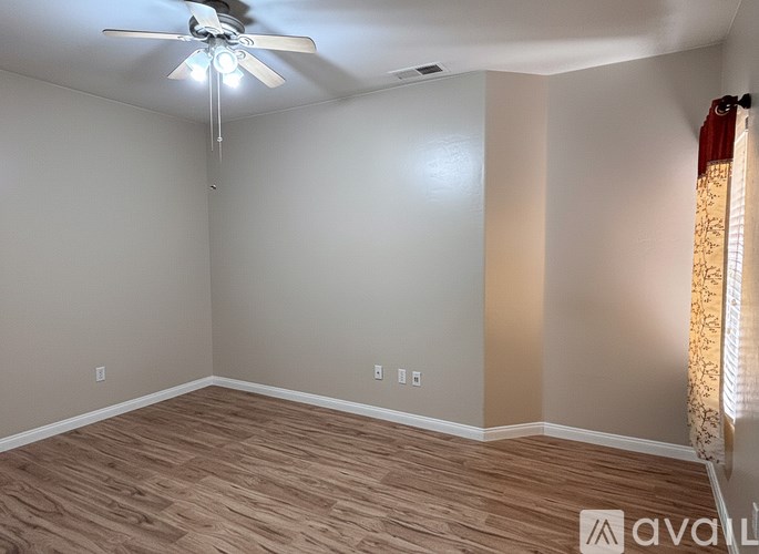A room with a ceiling fan and wooden flooring.