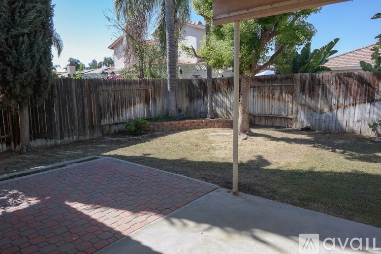 A backyard with a brick patio and a wooden fence.