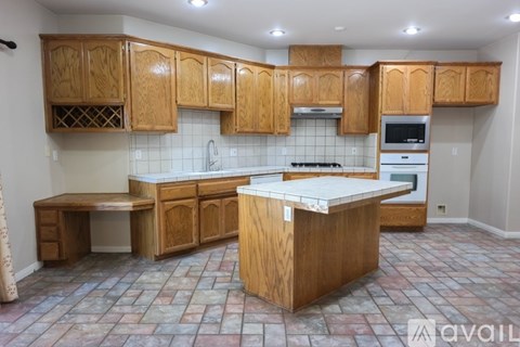 A kitchen with wooden cabinets and a tiled floor.