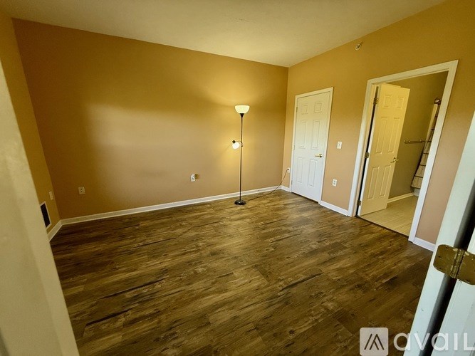 A room with wooden flooring and a lamp on the floor.