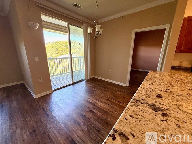 A room with wooden flooring and a balcony with a view of trees.