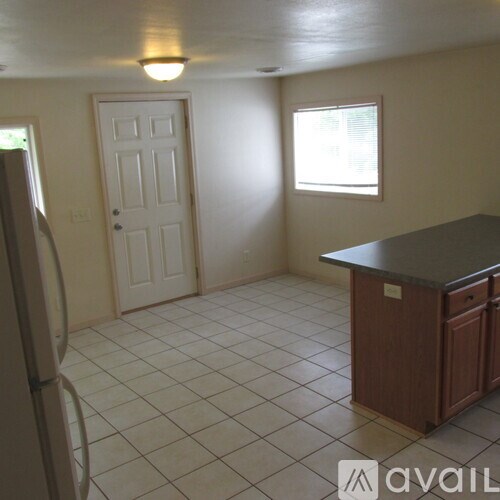 A kitchen with a refrigerator, a door, and a window.