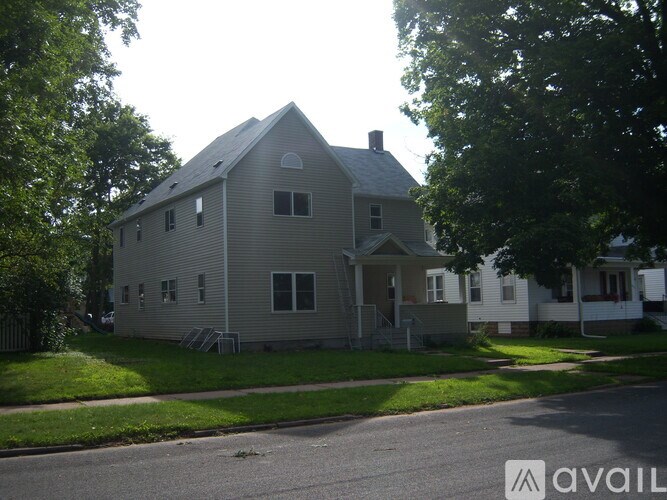 A house with a grey facade is surrounded by greenery.