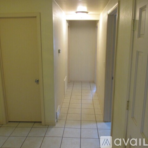 A hallway with tiled floors and white walls.
