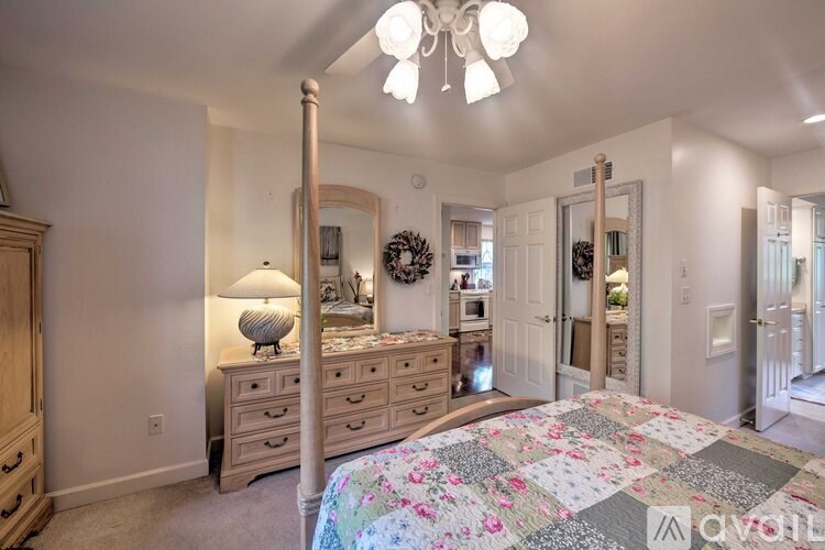 A bedroom with a large bed, a chandelier, and a dresser with a lamp on it.