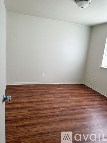 A room with wooden flooring and a door on the left.