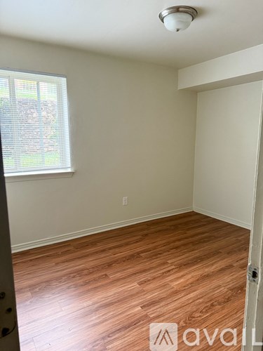 A room with wooden flooring and a window with blinds.