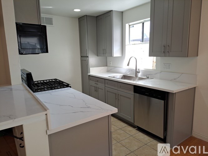 A kitchen with a white counter top and a black microwave.