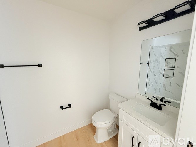 A white bathroom with a toilet, sink and mirror.