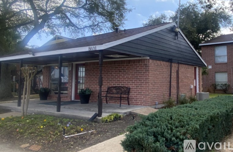 A house with a black roof and a porch with a bench.