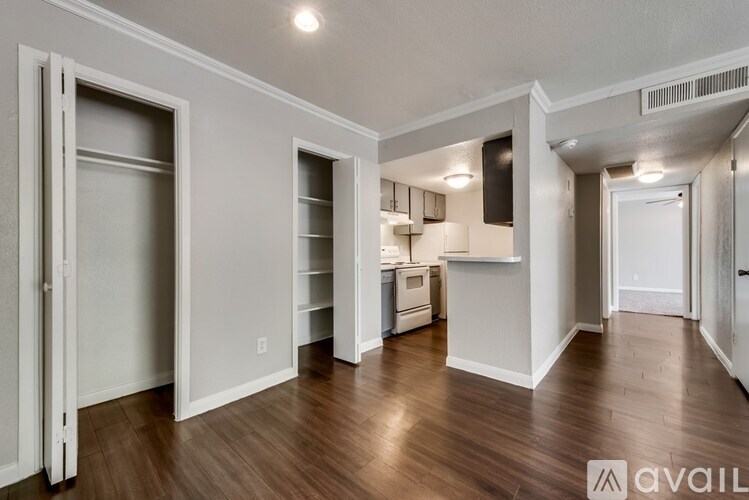 A spacious, empty apartment with wood flooring and white walls.