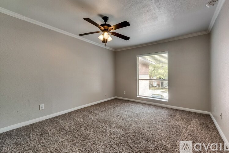 A room with a ceiling fan and carpeted floor.