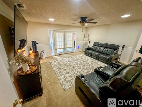 A living room with a black leather couch and a ceiling fan.