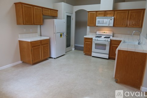 A kitchen with white appliances and wooden cabinets.