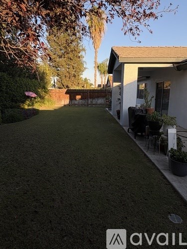 A house with a lawn and a patio with chairs and a table.