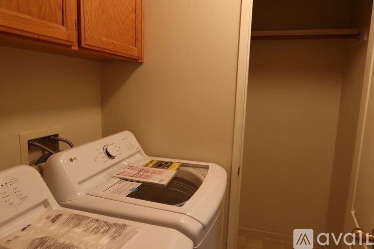 A white dryer is in a small room with wooden cabinets.