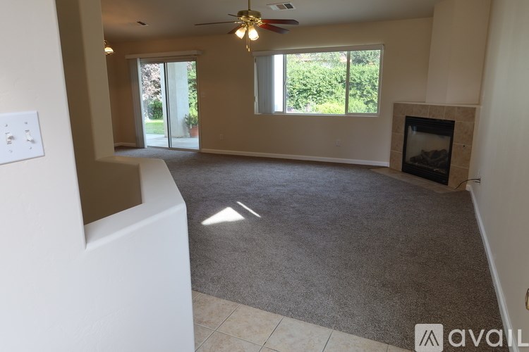 A living room with a fireplace and a ceiling fan.