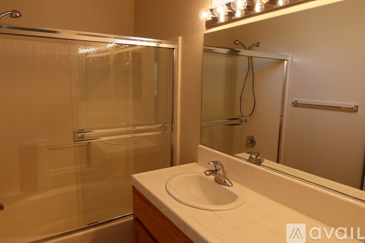 A bathroom with a sink, mirror, and shower.