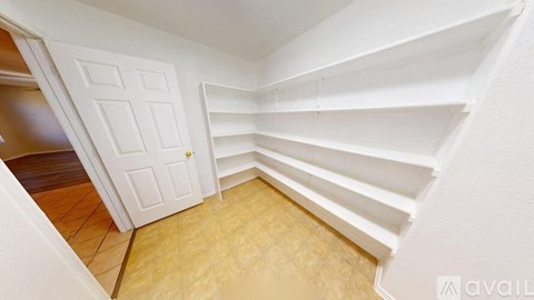 A white door is in a room with a wooden floor and white walls.