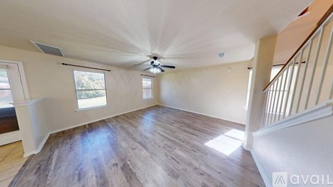 A room with a ceiling fan and wooden flooring.